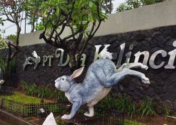 MEMOTRET: Seorang pengendara sedang memotret ikon pabrik Dua Kelinci yang ada di pagar depan ( Istimewa I harianmuria.com)