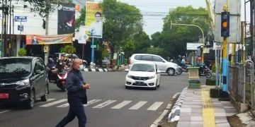 Menyebrang: Seorang warga menyebrang di traffic light perempatan Bleber yang hanya warna kuning pada Jumat (Istimewa I Harianmuria.com)