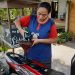 MELAYANI: Sumarni, penjual bensin eceran sedang melayani pembeli. (Lilik Yuliantoro/Harianmuria.com)