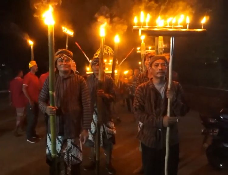 MENERANGKAN: Masyarakat Desa Soneyan dengan mengenakan pakaian batik lurik dengan memegang obor saat Festival Lamporan. (Arif Febriyanto/Harianmuria.com)
