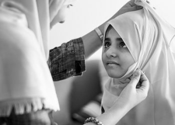 Muslim mom teaching daughter how to wear a Hijab