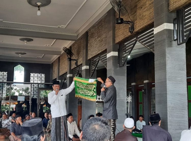 MEMAMERKAN: Juru kunci Makam Syekh Ronggo Kusumo menunjukkan potongan kain kelambu yang dilelang di hadapan masyarakat yang datang. (Aziz Afifi/Harianmuria.com)