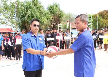 SIMBOLIS: Ketua PBVSI Jepara AKBP Warsono (kiri) menyerahkan bola voli kepada Ketua pelaksana Nur Rohmad (kanan) sebagai tanda dibukanya perhelatan Kualifikasi Porprov Voli Pasir. (Muslichul Basid/Harianmuria.com)