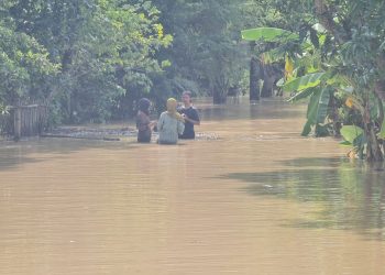 BANJIR: Beberapa orang terjebak banjir di salah satu kecamatan di Kabupaten Pati yang terjadi pada Sabtu (15/10). (Aziz Afifi/Harianmuria.com)