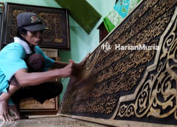 Pekerja bengkel ukir Khasanah sedang mengecat pesanan ukiran kaligrafi. (Azizi Afifi/Harianmuria.com)