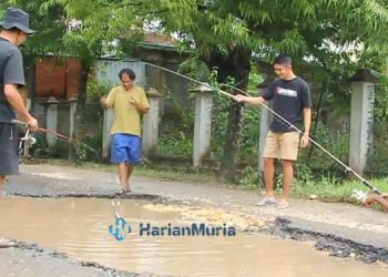 PROTES: Beberapa warga Kelurahan Ngawen, Kecamatan Ngawen, Kabupaten Blora saat melakukan aksi protes dengan mancing di tengah kubangan jalan belum lama ini.(Subkhan/Harianmuria.com)