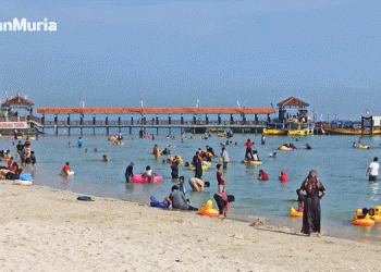 Anak-anak pengunjung Pantai Bandengan terlihat sedang bermain air dengan menggunakan alat pelampung renang dan didampingi oleh orang tua mereka. (Tomi/Harianmuria.com)