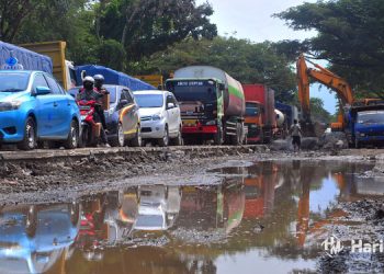 TERUS DIKEBUT: Perbaikan jalan di jalur Pantura Desa Raci, Batangan, Juwana, Pati, Jawa Tengah, Senin (3/4) terkendala hujan dan menyebabkan genangan air. (Mutia/Harianmuria.com)