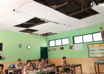 MEMPRIHATINKAN: Seorang guru menunjukkan kondisi atap SDN Bermi 03 yang ambrol dan tak tertangani karena minimnya jumlah siswa, Kamis (25/5). (Mishbah/Harianmuria.com)