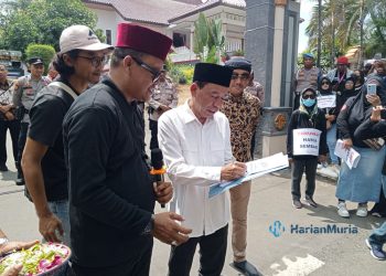 KESEPAKATAN: Ketua Komisi A DPRD Pati, Bambang Susilo saat menandatangani surat tuntutan dari massa aksi yang melakukan demonsi depan gedung DPRD Pati, Jumat 1 Maret 2024. (Setyo Nugroho/Harianmuria.com)