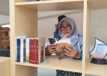 Seorang pengunjung Perpusda Rembang sedang fokus membaca buku di perpustakaan. (Lingkar Network | Harianmuria.com)
