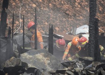Petugas pemadam kebakaran masih memadamkan bara api yang menyala di sela bangunan kios blok D Pasar Induk Cepu yang terbakar pada Minggu, 26 Januari 2025. (Harianmuria.com)