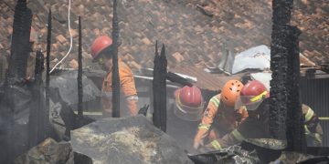 Petugas pemadam kebakaran masih memadamkan bara api yang menyala di sela bangunan kios blok D Pasar Induk Cepu yang terbakar pada Minggu, 26 Januari 2025. (Harianmuria.com)