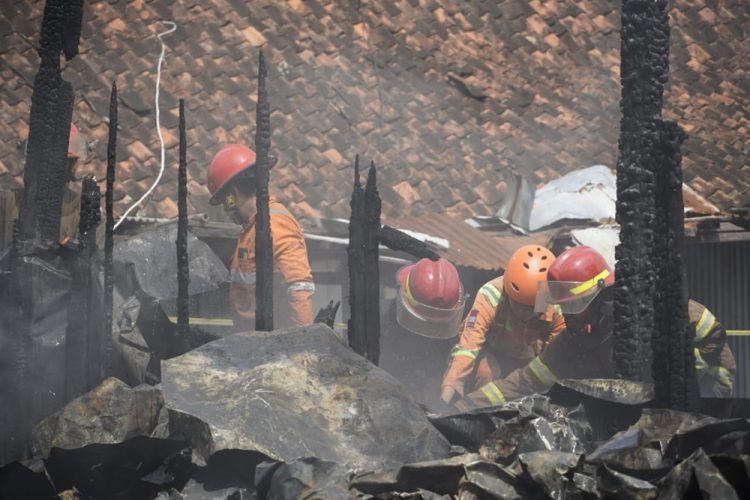 Petugas pemadam kebakaran masih memadamkan bara api yang menyala di sela bangunan kios blok D Pasar Induk Cepu yang terbakar pada Minggu, 26 Januari 2025. (Harianmuria.com)