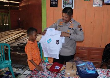 Kapolres Grobogan AKBP Ike Yulianto Wicaksono menyerahkan seragam sekolah kepada Slamet Riyadi. (Dok. Polres Grobogan/Harianmuria.com)