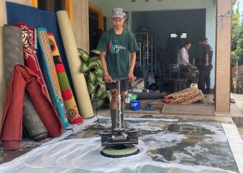 Seorang pekerja mencuci karpet dengan vacuum cleaner. (Fahtur Rohman/Harianmuria.com)
