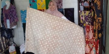 Pemilik Batik Widji, Widji Astutik, menunjukan karya batik yang dihasilkan dengan pewarna alami lumpur sawah. (Arvian Maulana/Harianmuria.com)